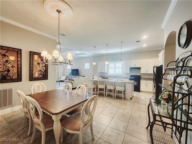 tiled dining room featuring ornamental molding and a chandelier