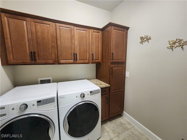 clothes washing area with cabinets, washer and dryer, and light tile patterned floors