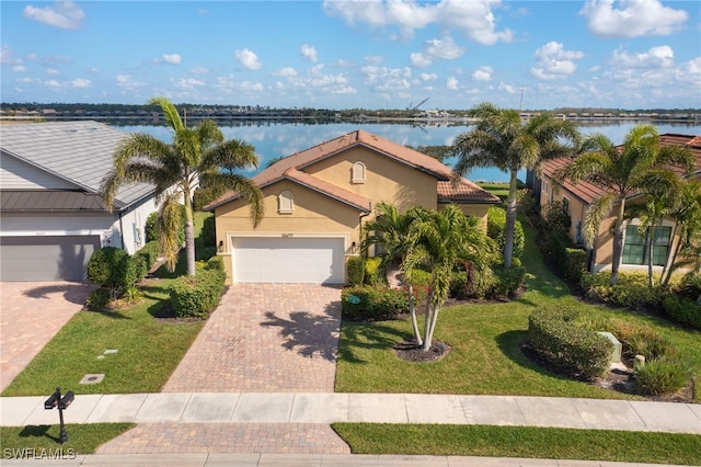 view of front of property featuring a garage, a front lawn, and a water view