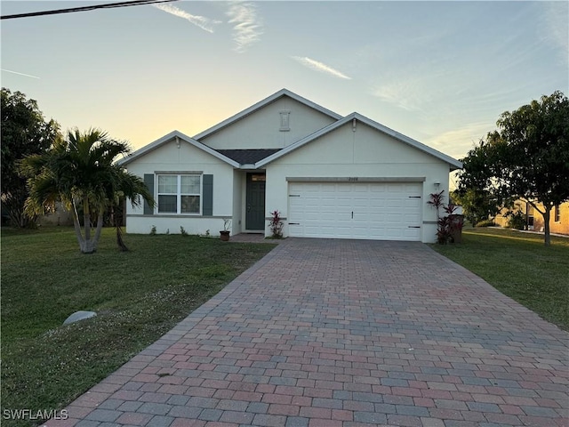 ranch-style home featuring decorative driveway, a lawn, an attached garage, and stucco siding