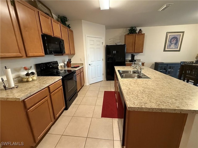 kitchen with light tile patterned floors, a kitchen island with sink, light countertops, black appliances, and a sink