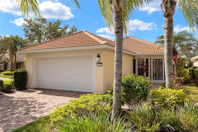 mediterranean / spanish house featuring a tiled roof, an attached garage, driveway, and stucco siding