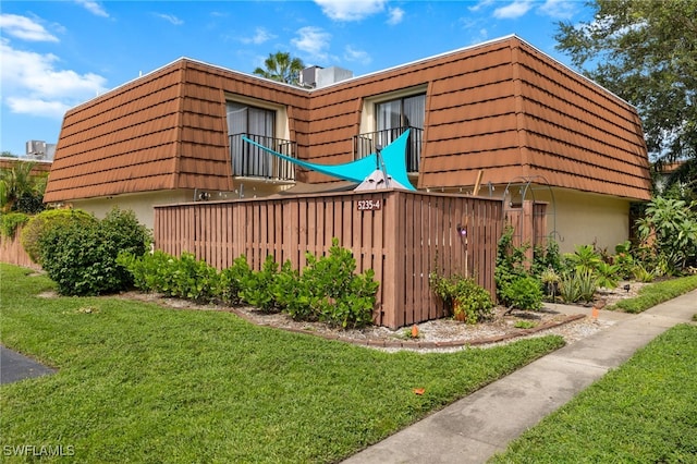 view of side of property featuring a balcony and a yard