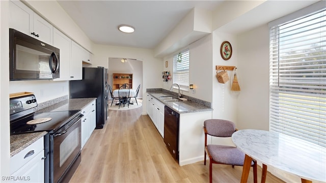 kitchen featuring sink, black appliances, light wood-type flooring, stone counters, and white cabinets