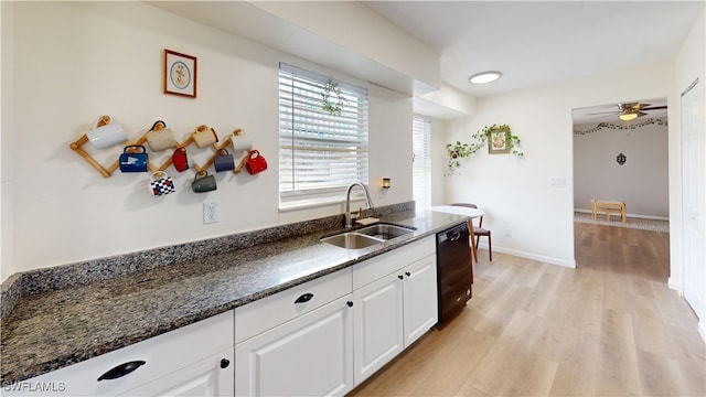 kitchen featuring sink, dark stone countertops, black dishwasher, light hardwood / wood-style floors, and white cabinets