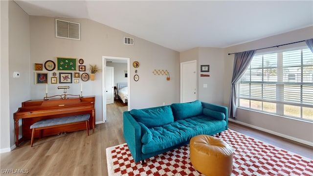 living room featuring vaulted ceiling, a healthy amount of sunlight, and light wood-type flooring