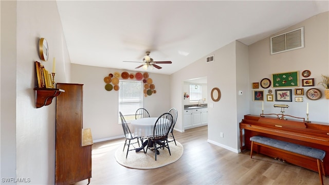 dining room with ceiling fan, vaulted ceiling, and light hardwood / wood-style flooring