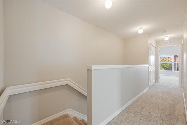 corridor with an upstairs landing, light carpet, visible vents, and baseboards