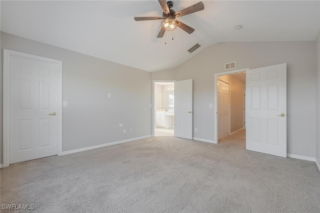 unfurnished bedroom with lofted ceiling, visible vents, light carpet, and baseboards