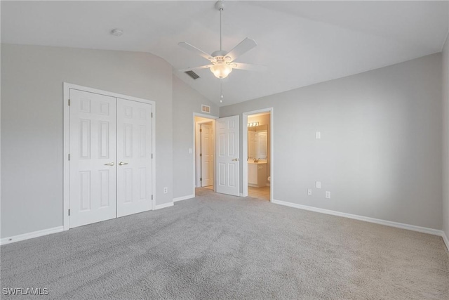 unfurnished bedroom featuring lofted ceiling, light colored carpet, visible vents, baseboards, and a closet