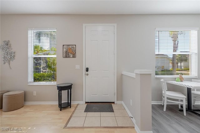 foyer entrance featuring light wood finished floors, baseboards, and a wealth of natural light