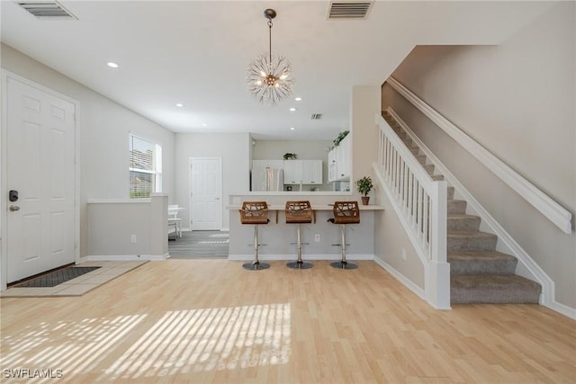 entryway with light wood-type flooring, stairway, and visible vents