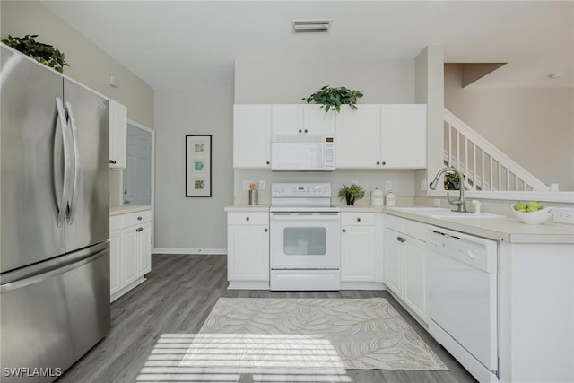 kitchen with white appliances, a sink, visible vents, white cabinets, and light countertops