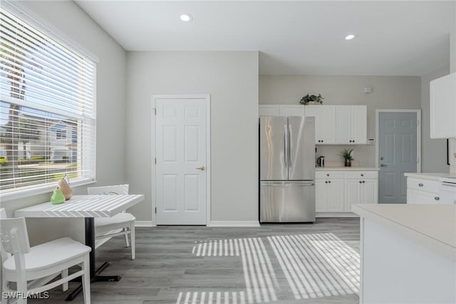 kitchen with light wood-style floors, white cabinets, light countertops, and freestanding refrigerator