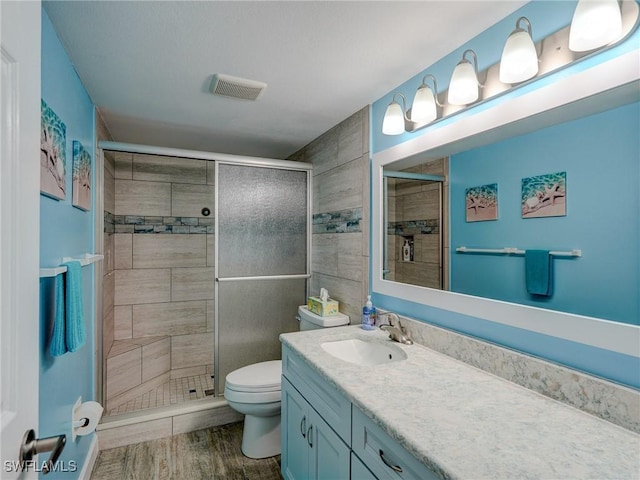 bathroom with an enclosed shower, vanity, wood-type flooring, and toilet