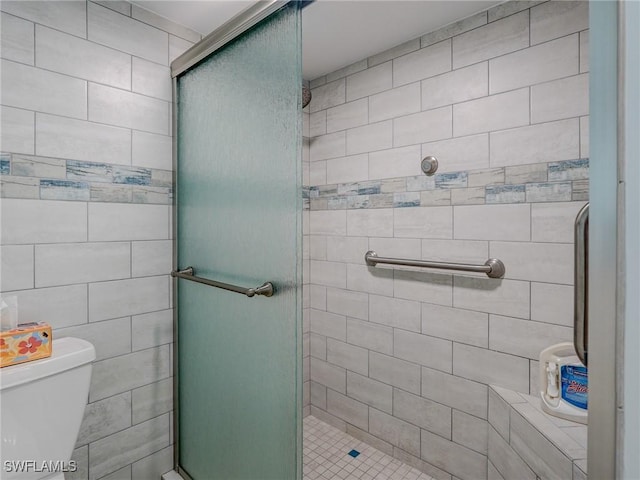 bathroom featuring toilet and a shower with shower door