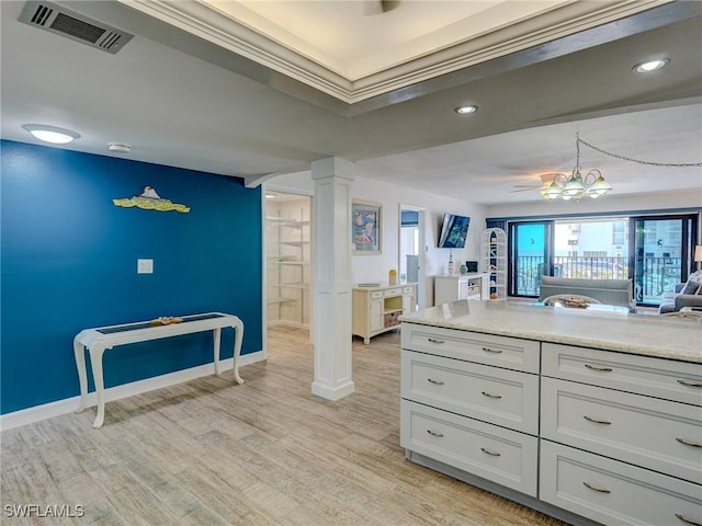 kitchen featuring ornate columns, white cabinets, light wood-type flooring, and decorative light fixtures