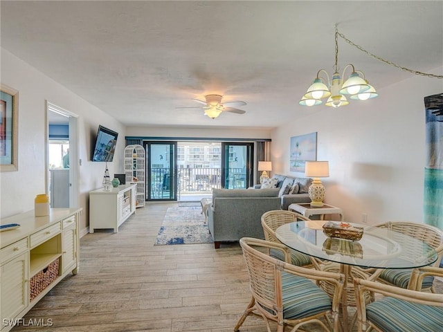 dining space with ceiling fan with notable chandelier, plenty of natural light, and light wood-type flooring