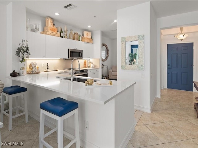 1045 Tarpon Cove Dr Unit 102, Naples, FL 34110 - kitchen with light countertops, appliances with stainless steel finishes, a breakfast bar area, and visible vents