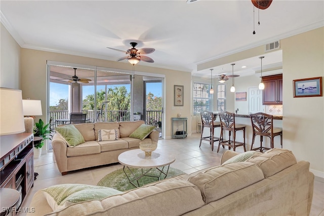 tiled living room with ornamental molding and ceiling fan