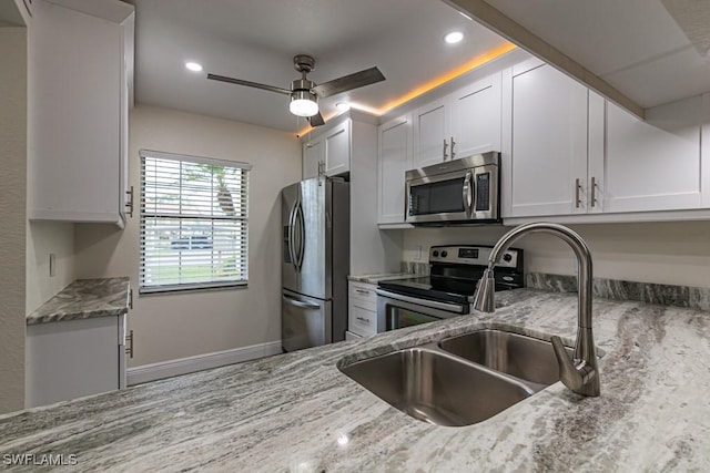 kitchen featuring light stone counters, recessed lighting, a sink, white cabinetry, and appliances with stainless steel finishes