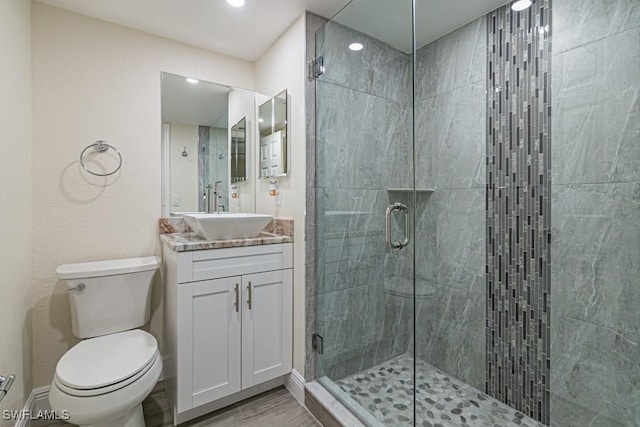 bathroom with vanity, a shower stall, toilet, and baseboards