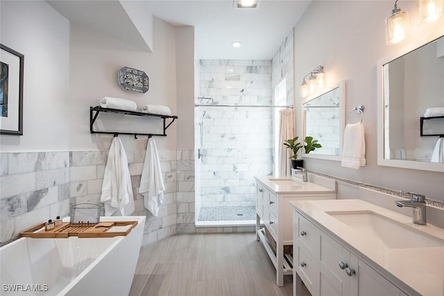 bathroom featuring shower with separate bathtub, tile walls, and vanity