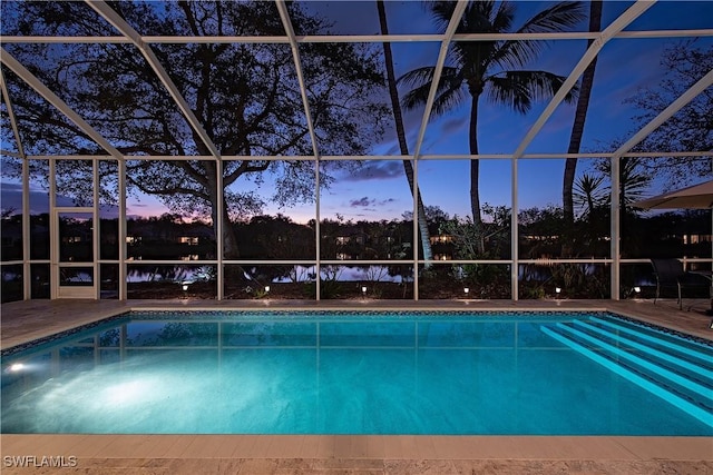 pool at dusk featuring a patio and glass enclosure