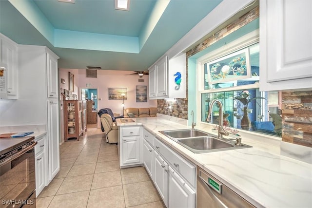 kitchen with a tray ceiling, sink, and white cabinets