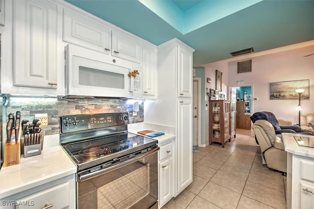 kitchen with black / electric stove, backsplash, light tile patterned floors, and white cabinets