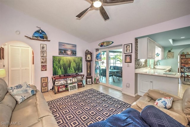 living room with vaulted ceiling, light tile patterned floors, arched walkways, and ceiling fan