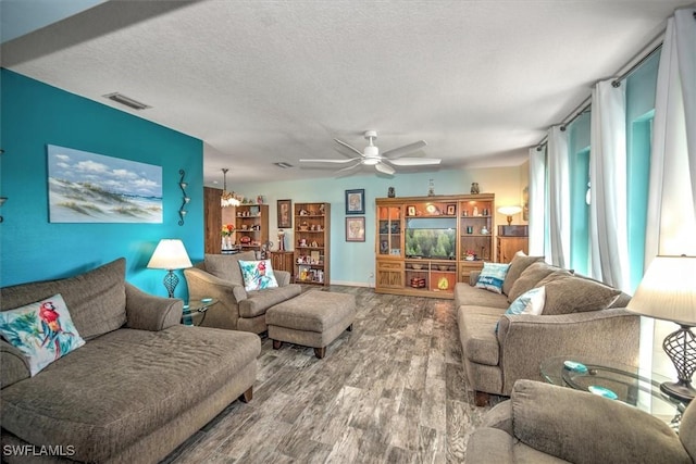 living room featuring hardwood / wood-style flooring, ceiling fan, and a textured ceiling