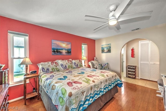 bedroom featuring ceiling fan, hardwood / wood-style floors, a textured ceiling, and a closet