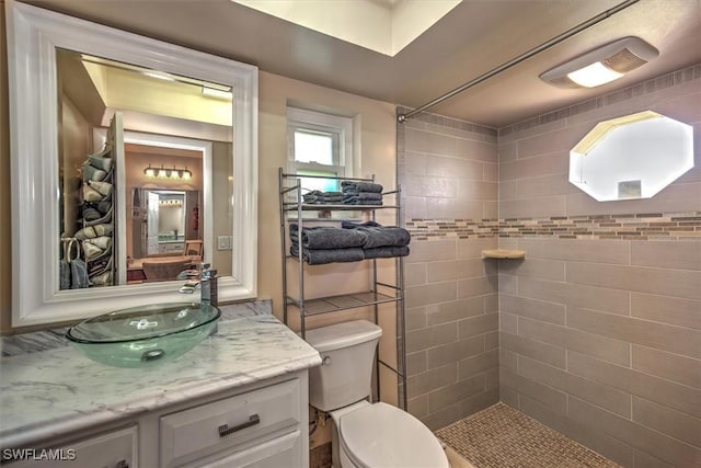 bathroom with vanity, toilet, and a tile shower