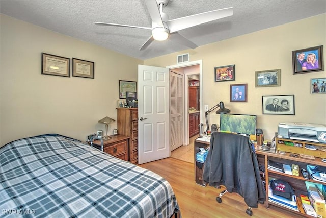 bedroom featuring ceiling fan, a textured ceiling, and light hardwood / wood-style flooring