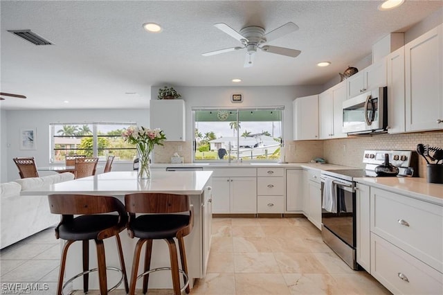 kitchen featuring white cabinetry, a wealth of natural light, a breakfast bar, and appliances with stainless steel finishes