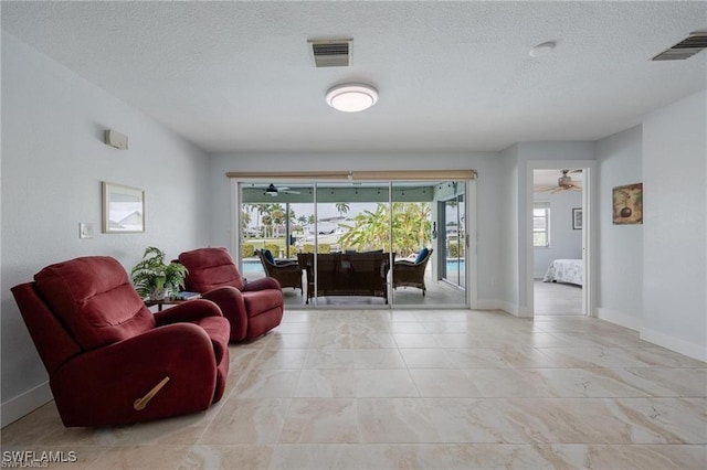 living room with ceiling fan and a textured ceiling