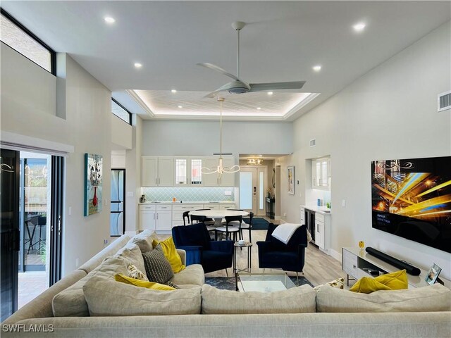 living room with wine cooler, a towering ceiling, ceiling fan, and light wood-type flooring