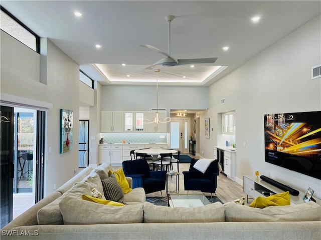 living room with light wood-style flooring, recessed lighting, beverage cooler, a towering ceiling, and a ceiling fan