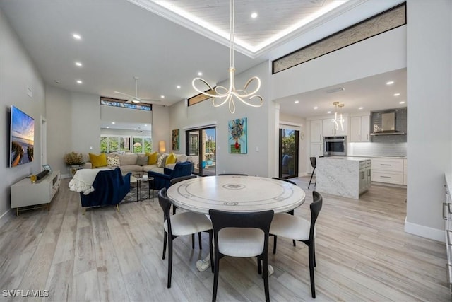 dining area with baseboards, a high ceiling, light wood-type flooring, a notable chandelier, and recessed lighting