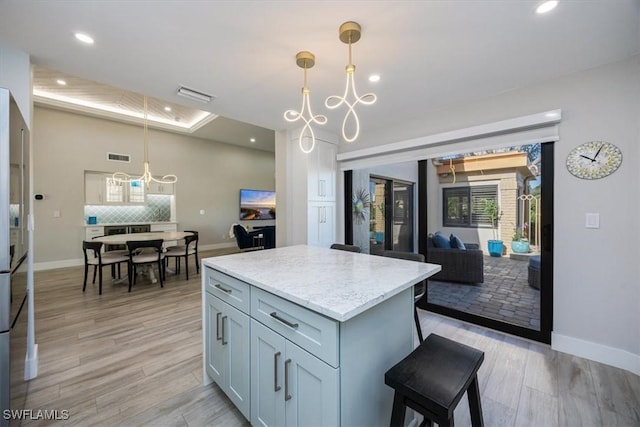 kitchen with baseboards, visible vents, open floor plan, decorative light fixtures, and a center island