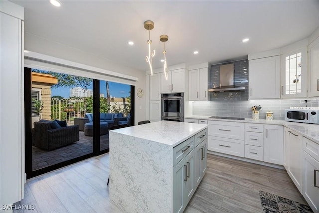 kitchen featuring tasteful backsplash, white microwave, double oven, white cabinets, and wall chimney exhaust hood