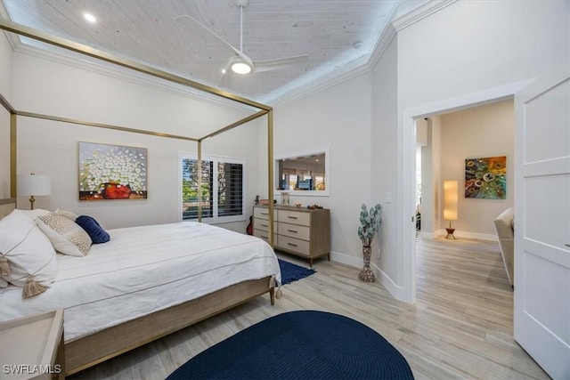 bedroom featuring ornamental molding, a towering ceiling, light wood-style flooring, and baseboards