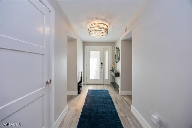 doorway with a chandelier and light wood-type flooring