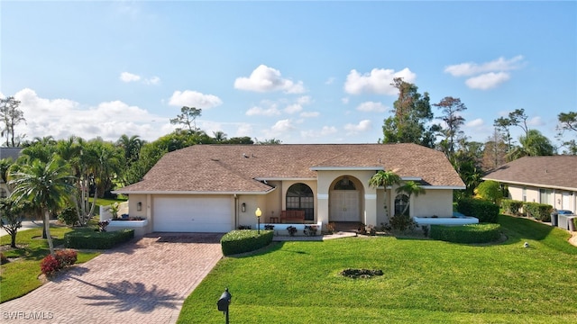 view of front facade featuring a front yard, decorative driveway, an attached garage, and stucco siding