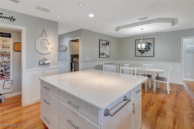 kitchen with white cabinetry, a kitchen island, light hardwood / wood-style flooring, and decorative light fixtures