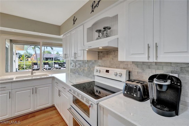 kitchen featuring sink, light hardwood / wood-style flooring, double oven range, tasteful backsplash, and white cabinets