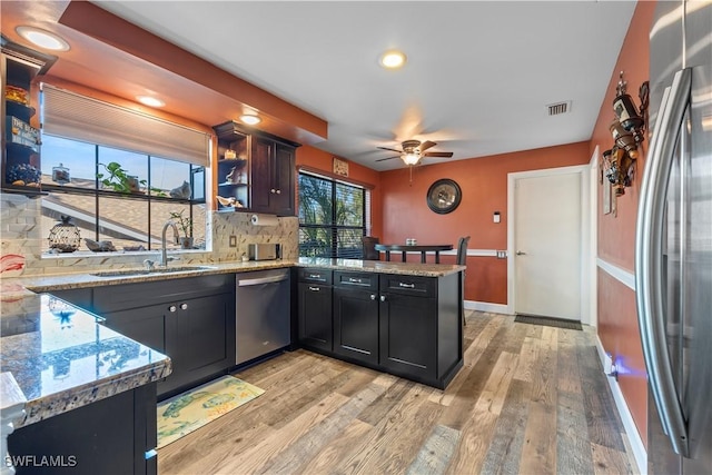 kitchen with appliances with stainless steel finishes, kitchen peninsula, sink, and light stone countertops