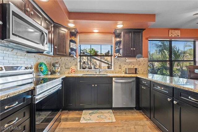 kitchen with dark brown cabinetry, sink, tasteful backsplash, appliances with stainless steel finishes, and light stone countertops