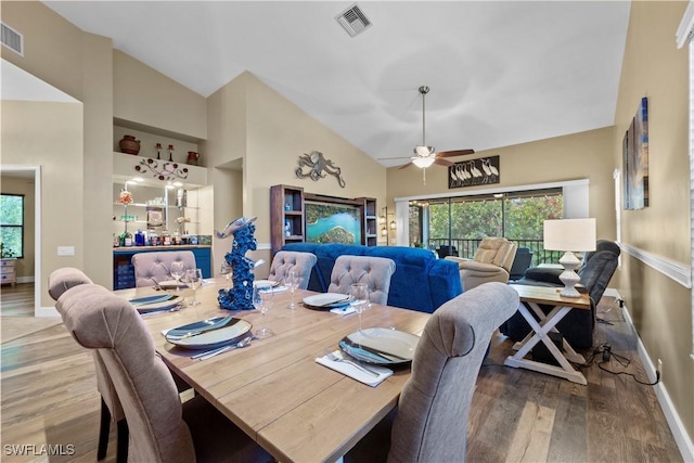 dining space with hardwood / wood-style flooring, ceiling fan, and high vaulted ceiling